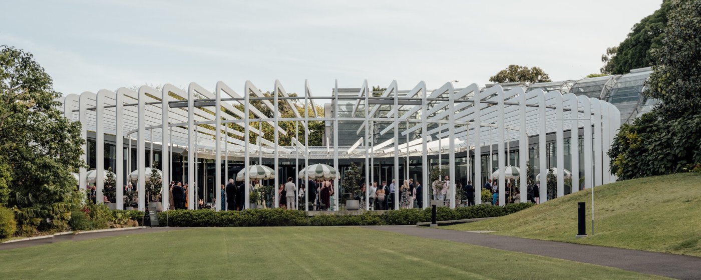 The Calyx venue exterior at the Royal Botanic Garden Sydney, with guests gathered beneath its white pergola structure